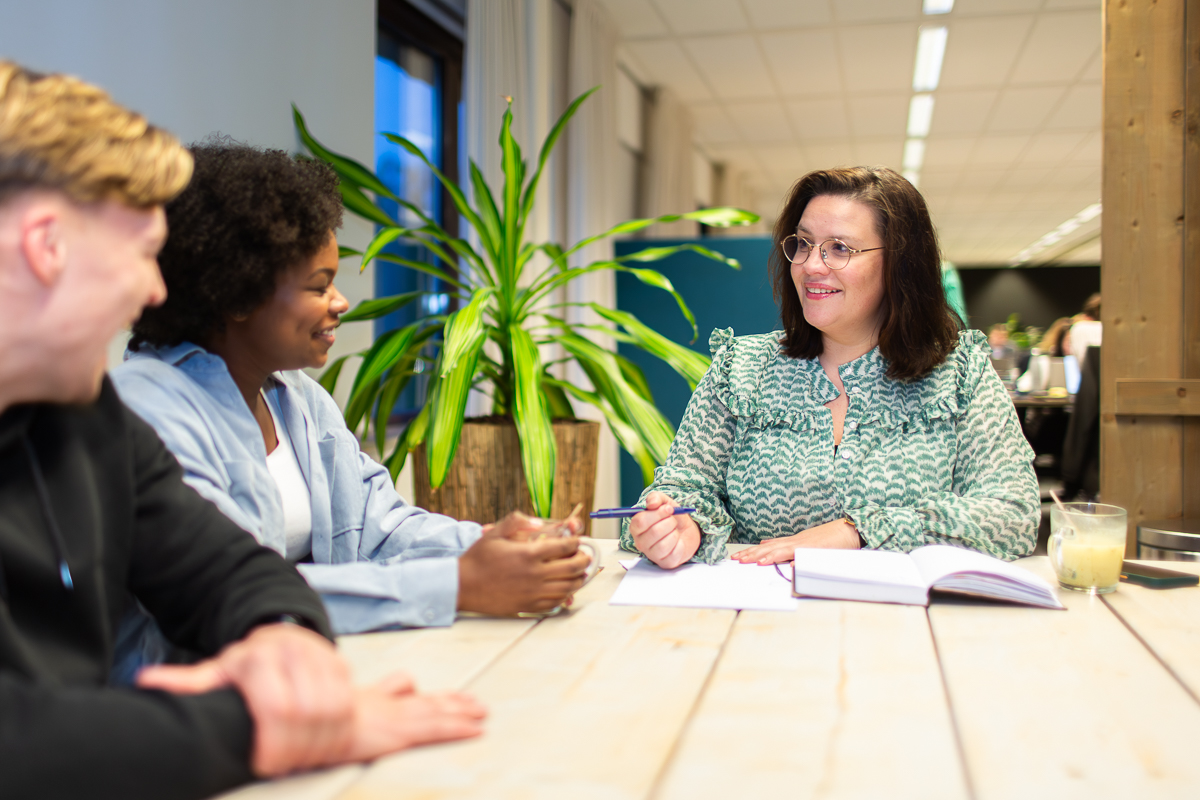 Vrouw praat met jongen en vrouw aan een tafel